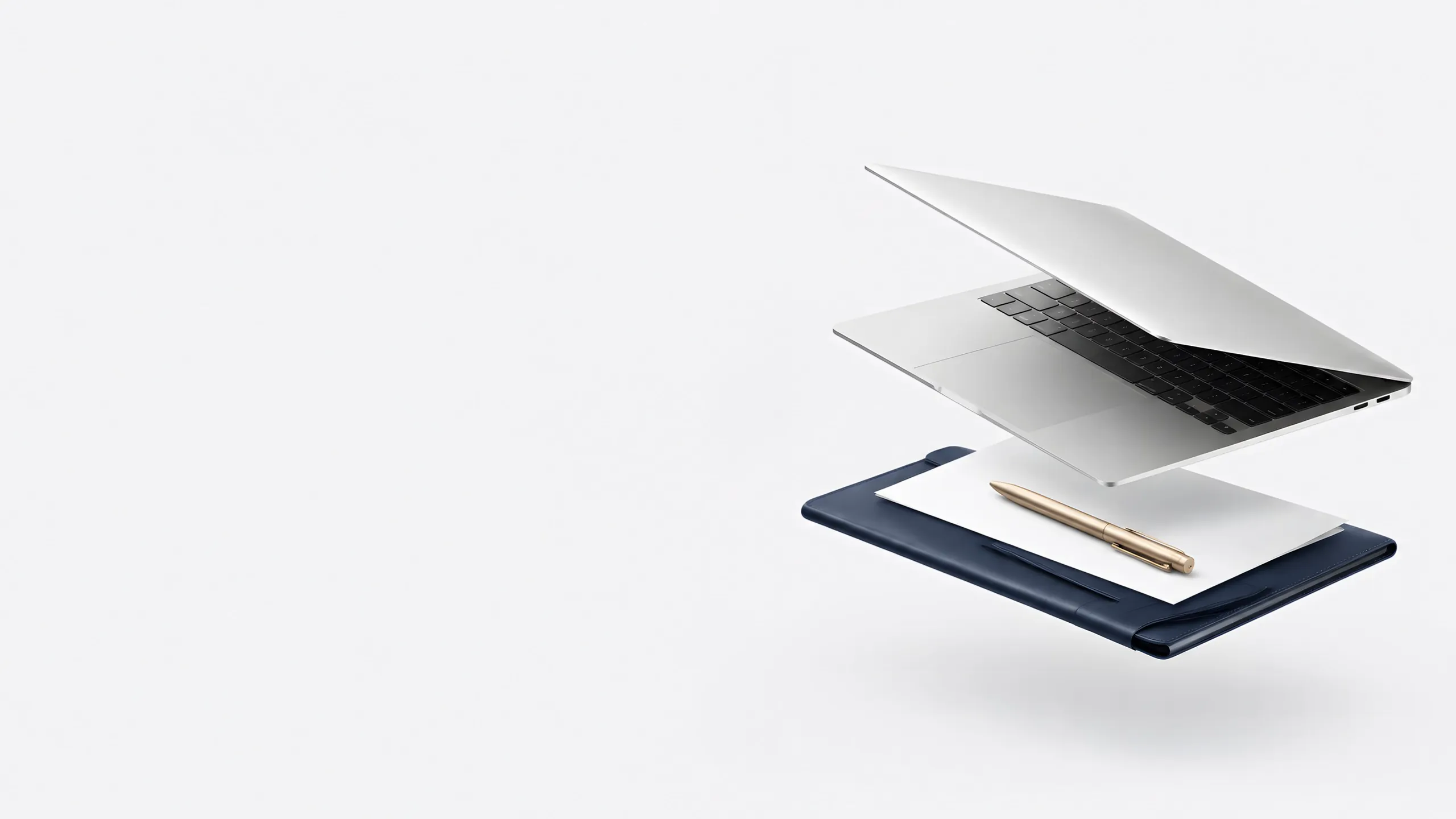 A silver laptop resting on a navy leather folio with paperwork and a gold pen